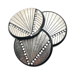 May include: Three circular buttons featuring a silver-toned sunburst pattern on a black base. Each button is accented with a diagonal line of small, clear, sparkling rhinestones that cut across the metallic fan-like design.