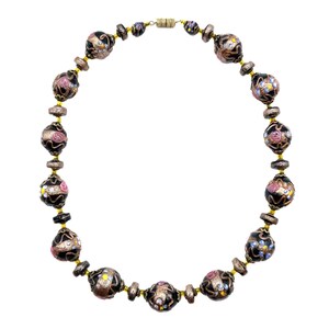 May include: A necklace with black and gold beads, decorated with floral and glitter details. The necklace has a gold-tone clasp and connecting chain. The beads are round and oval, with pink, white, and yellow floral designs.
