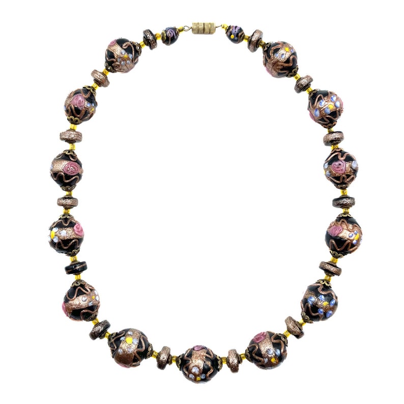 May include: A necklace with black and gold beads, decorated with floral and glitter details. The necklace has a gold-tone clasp and connecting chain. The beads are round and oval, with pink, white, and yellow floral designs.