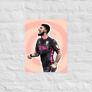 May include: Illustration of a soccer player in a black and pink jersey with the text "32 Red". The player is looking up and to the right with an open mouth. The background is a light orange circle.