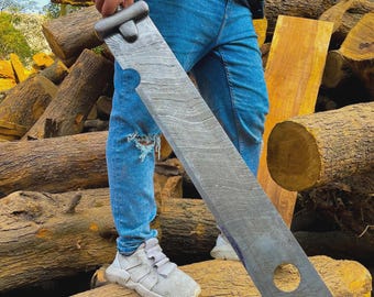 Puede incluir: Una espada grande de metal gris con una hoja ancha y un agujero circular cerca de la punta. El mango es negro y plateado. La espada se sostiene frente a un fondo de troncos.