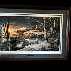 May include: Framed winter landscape print featuring a horse-drawn carriage, a stone bridge, and a church in the distance. The artwork is set against a snowy backdrop with a sunset, framed in a dark wood frame.