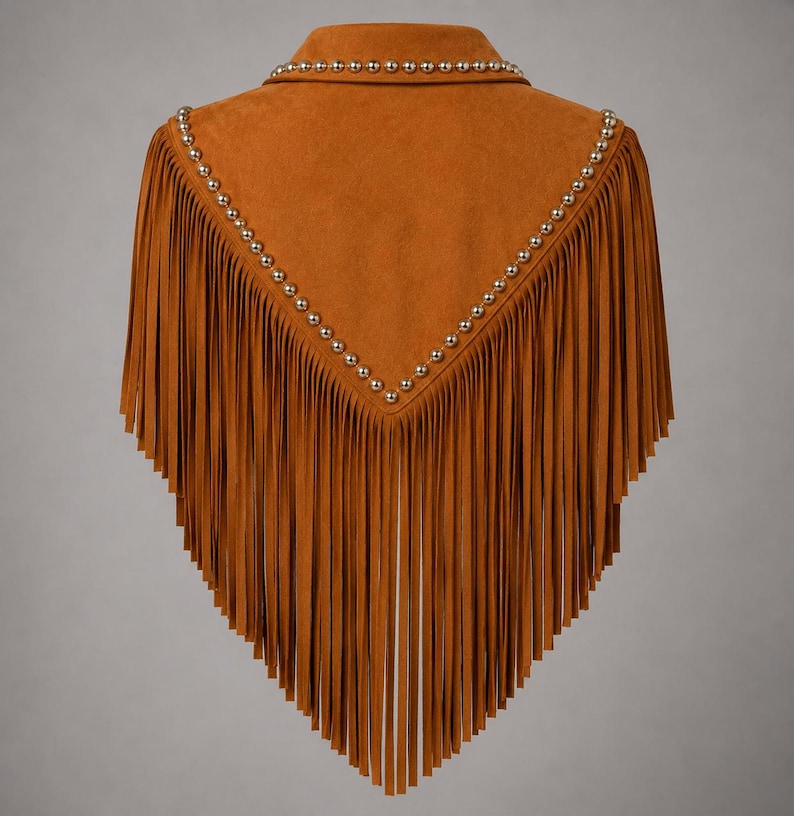 May include: A tan suede cape featuring a V-shaped yoke adorned with metallic silver studs along the edges. The garment is finished with long, vertical fringe detailing that extends from the studded yoke down to the bottom hemline.