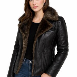 May include: Black leather jacket with a brown faux fur collar and lining. The jacket has a classic design with a zip closure and a tailored fit. The model is wearing blue jeans and a black top.