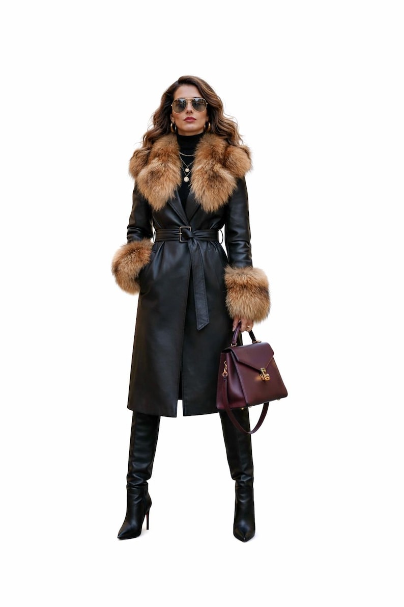 Peut inclure: Un manteau en cuir noir avec un col et des poignets en fourrure. Le manteau est ceintur&eacute; &agrave; la taille et associ&eacute; &agrave; des bottes noires et un sac &agrave; main bordeaux. La femme porte des lunettes de soleil et des bijoux.