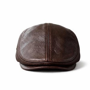 May include: A brown leather flat cap with a rounded crown and a small, stiff brim. The cap has a smooth, textured surface and a classic, timeless design. The hat is a stylish accessory.