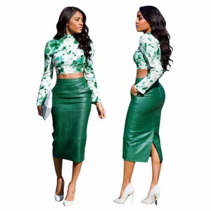Op de afbeelding: Een tweedelige outfit met een groene leren potloodrok en een crop top met lange mouwen. De top heeft een witte basis met groene tie-dye patronen. De outfit wordt gecombineerd met witte hakken.
