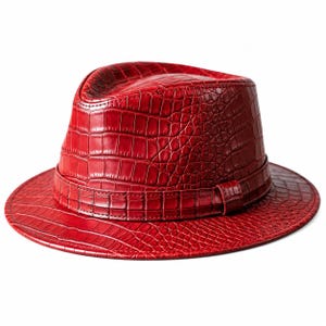 Pode incluir: Um chapéu fedora vermelho vibrante com um padrão de textura de pele de crocodilo em toda a superfície. O chapéu inclui uma faixa vermelha a condizer à volta da base da copa, com uma aba estruturada e um design de topo vincado clássico.