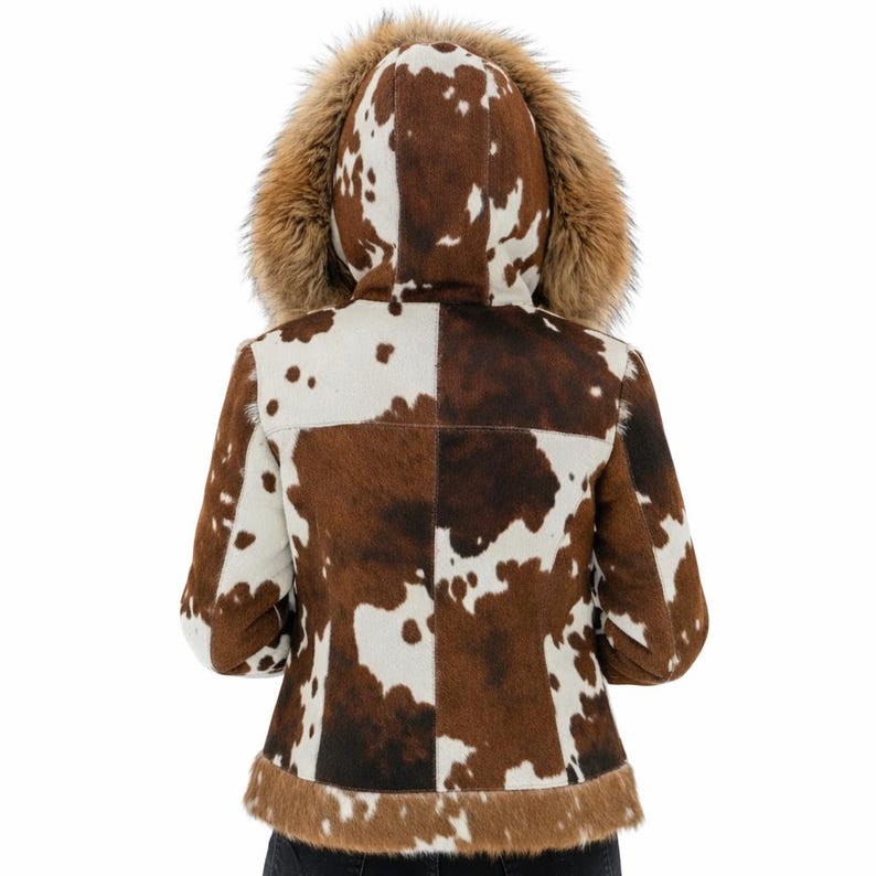 May include: A cowhide jacket with a brown and white spotted pattern. The jacket has a fur-lined hood and trim. The back of the jacket is divided into four squares. The sleeves are three-quarter length.