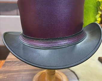 Puede incluir: Un sombrero de copa con una corona morada oscura y un ala negra. El sombrero se exhibe en un soporte de madera. El texto "rusticleatherhouse" es visible en el sombrero. El sombrero es de cuero.