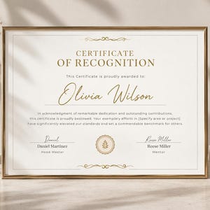 Op de afbeelding: Een rechthoekig certificaat van erkenning in een dunne gouden lijst. Het document bevat gouden tekst met "CERTIFICATE OF RECOGNITION" en "Olivia Wilson" in cursief schrift, met gedrukte lijnen voor namen en titels zoals Daniel Martinez.