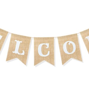 May include: A decorative banner featuring seven individual pennant flags made of tan burlap material. Each flag displays a single white letter, collectively spelling out the word WELCOME. The flags are strung together on a thin, light-colored cord.