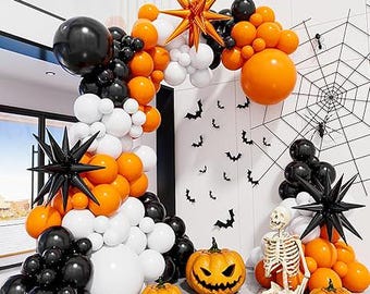 May include: A Halloween-themed balloon arch in black, orange, and white, with starburst decorations and carved pumpkins. A skeleton and spiderweb complete the festive scene.