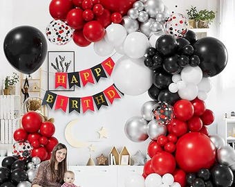 May include: A festive birthday party scene with red, black, white, and silver balloons. A banner reads "Happy Birthday." A woman and a baby are seated in front of the decorations.