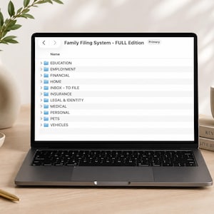 Peut inclure: Un écran d'ordinateur portable affichant une interface de gestion de fichiers numériques intitulée Family Filing System - FULL Edition. La liste comprend des dossiers pour Education, Employment, Financial, Home, Inbox - To File, Insurance, Legal & Identity, Medical, Personal, Pets et Vehicles.