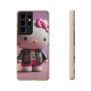 May include: A phone case featuring a 3D rendering of Hello Kitty wearing a black leather jacket and pink shorts. The case has a pink background and a side view showing a textured, light-colored edge.