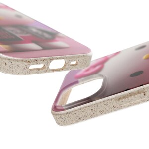 May include: Two phone cases with a pink and white design. The cases have a speckled, off-white border and cutouts for the camera and charging port. The design on the case is slightly blurred, but appears to be a cartoon character.