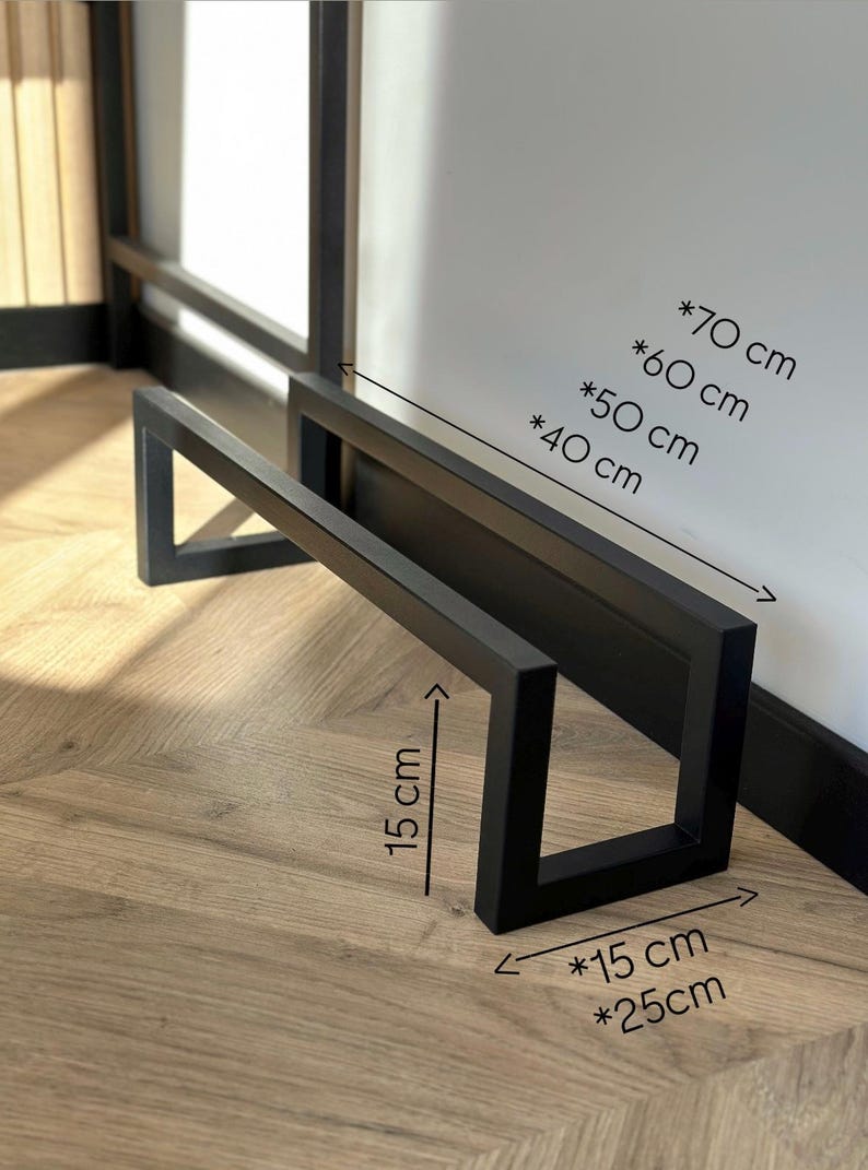 May include: Black metal shelf brackets with dimensions of 15 cm x 25 cm and heights of 40 cm, 50 cm, 60 cm, and 70 cm. The brackets are displayed on a wooden floor, showcasing their modern design.