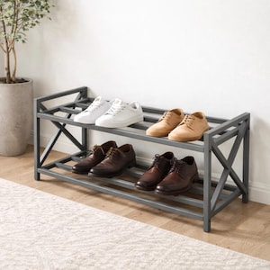 Puede incluir: Un zapatero de metal gris de dos niveles, que contiene varios pares de zapatos. Los zapatos incluyen zapatillas blancas, zapatos de ante color canela y zapatos de vestir de cuero marrón. El zapatero está contra una pared blanca y una alfombra clara.