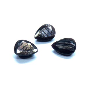 May include: Three dark, teardrop-shaped gemstones with a polished, faceted surface. The gems have a deep, reddish-brown color with internal light reflections, set against a white background. These gemstones are suitable for jewelry making.