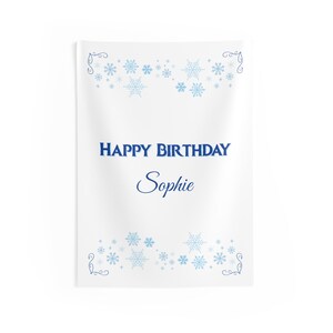 Puede incluir: Bandera rectangular blanca con texto azul que dice "HAPPY BIRTHDAY Sophie". La bandera est&aacute; decorada con copos de nieve azules y adornos decorativos en la parte superior e inferior. Es una decoraci&oacute;n de cumplea&ntilde;os.