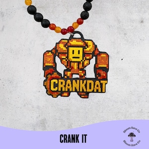 Puede incluir: Un collar con un colgante que representa un robot pixelado en naranja y amarillo, con el texto "CRANKDAT". El collar tiene un hilo de cuentas con cuentas negras, naranjas y amarillas. La frase "CRANK IT" está en la parte inferior de la imagen.