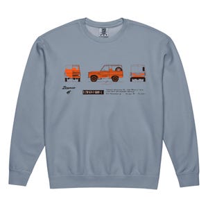 Puede incluir: Sudadera azul claro con un diagrama naranja de un SUV Bronco vintage. El diagrama muestra el vehículo desde la parte delantera, lateral y trasera. La palabra "Bronco" está encima del diagrama, con texto y números debajo.