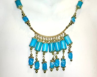 May include: A turquoise and gold necklace with a cascading design. The necklace features a row of rectangular turquoise stones with gold accents, followed by a row of smaller, round turquoise stones.