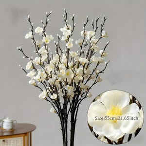 May include: Artificial white cherry blossom branches with dark brown stems. The branches are 21.65 inches tall and feature a close-up of a single flower. The flower has white petals and a yellow center.