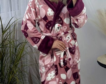 Può includere: Accappatoio rosa con cappuccio con un motivo stravagante di personaggi e forme di cartoni animati. L'accappatoio ha un bordo bordeaux sul cappuccio, sui polsini e sulla cintura. Realizzato in materiale morbido e felpato, con cintura abbinata.