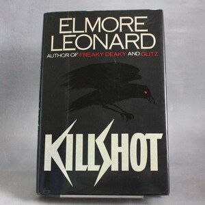 Puede incluir: Un libro de tapa dura negro titulado "KILLSHOT" de Elmore Leonard. La portada presenta texto blanco y una ilustración de un pájaro negro estilizado. El nombre del autor y otros títulos de libros también son visibles.