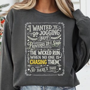 May include: Dark gray sweatshirt with a white graphic. The graphic reads "I wanted to go jogging but Proverbs 28:1 says 'The wicked run when no one is chasing them.' So there's that..."