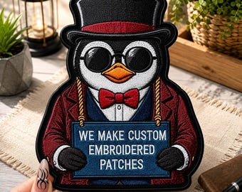 May include: An embroidered patch featuring a penguin wearing a black top hat with a red band, round sunglasses, and a red bow tie. The penguin wears a dark red jacket and holds a blue sign with the white text WE MAKE CUSTOM EMBROIDERED PATCHES.