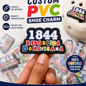 Può includere: Un charm per scarpe in PVC nero con il testo bianco 1844 sopra il testo multicolore REPÚBLICA DOMINICANA. Il charm ha uno sfondo nero ed è mostrato insieme ad altri charm identici e una scarpa bianca con fori.