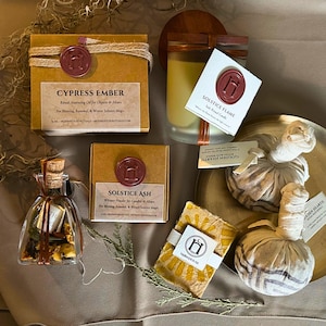 May include: An assortment of ritual items, including candles, powders, and oils. The items are packaged in brown boxes and glass bottles, sealed with red wax stamps. The text on the labels includes "Cypress Ember", "Solstice Flame", and "Golden Hearth".