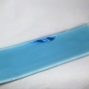 May include: A long, rectangular serving tray made of clear glass with a light blue base and a swirl of blue and white glass in the center.