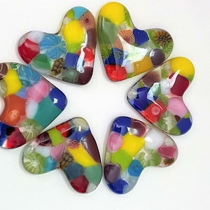 May include: Six colorful glass heart-shaped ornaments with a mosaic pattern. Each heart features a variety of colors, including red, yellow, green, blue, and white.
