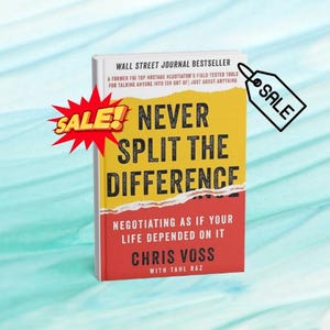 May include: A hardcover book titled "Never Split the Difference" with a yellow and red cover. The book is a Wall Street Journal bestseller and features the author Chris Voss. A red "SALE!" graphic and a black and white "SALE" tag are also present.