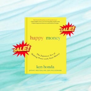 May include: A yellow book titled "happy money" with the subtitle "The Japanese Art of Making Peace with Your Money" by Ken Honda. The book has red "SALE!" stickers and a quote from Jack Canfield.
