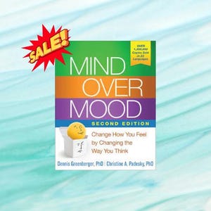 May include: A book titled "Mind Over Mood, Second Edition" with a green, orange, and purple cover. The cover features the title in white letters and a graphic of a smiling face. A red "SALE!" sticker is in the upper left corner.