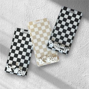 May include: Three rectangular badge holders with a checkered pattern. One is black and white, one is beige and white, and the third is black and white with the text "Psychiatric Nurse". The bottom of two badge holders have the text "X-Ray".