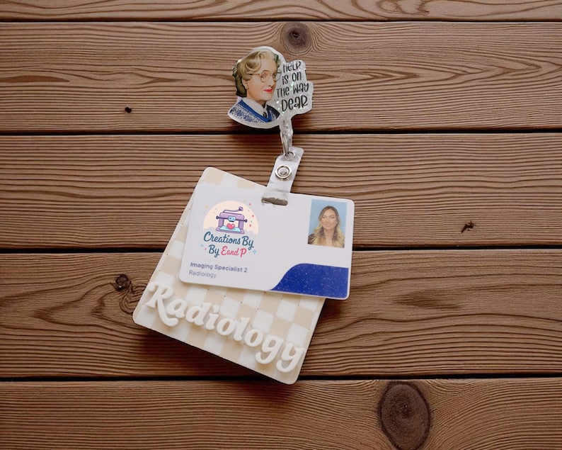 May include: A badge reel with a cartoon image of a woman with the text "Help is on the way dear." Below is a white and blue badge with the word "Radiology" and a photo of a woman.