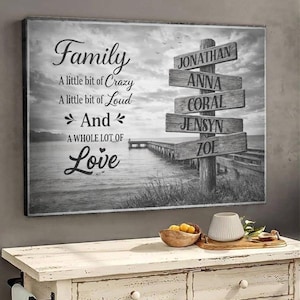 May include: Black and white canvas art with the words "Family" and "A little bit of Crazy, A little bit of Loud, And A WHOLE LOT OF Love." A wooden signpost displays names: Jonathan, Anna, Coral, Jensyn, and Zoe. The background shows a pier and water.