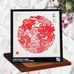 May include: Framed red paper cut art featuring a detailed dragon design within a circular frame. The artwork is set against a white background and framed in black. The text "Chinese intangible cultural heritage" is visible.