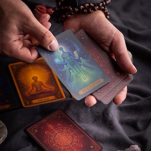 Pu&ograve; includere: Un mazzo di tarocchi con illustrazioni mistiche. Una carta, etichettata "THE REDEMPTION", presenta una figura con esseri eterei. Altre carte mostrano una figura che medita e un disegno circolare. Le carte sono tenute su uno sfondo grigio scuro.