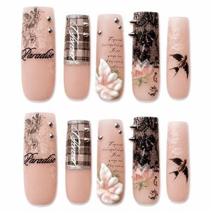 May include: A set of ten press-on nails in a long square shape with a nude base. Designs include black script text reading Paradise and Forever, a brown plaid pattern, silver studs, a 3D white flower, black lace overlay, and a black bird illustration.