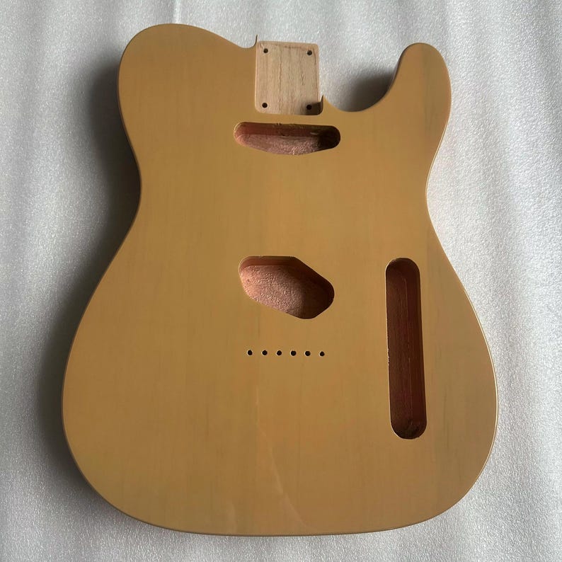 Puede incluir: Cuerpo de guitarra marr&oacute;n claro con recortes para pastillas, controles y m&aacute;stil. El cuerpo tiene un acabado liso y est&aacute; listo para el montaje. La veta de la madera es visible y el cuerpo est&aacute; dise&ntilde;ado para una guitarra estilo Telecaster.
