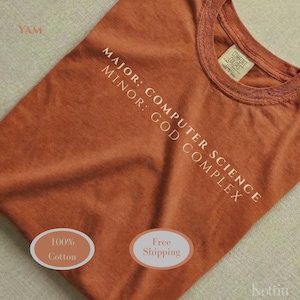 May include: Rust-colored t-shirt with the text "MAJOR: COMPUTER SCIENCE, MINOR: GOD COMPLEX" in white. The shirt is made of 100% cotton. The tag reads "Comfort Colors".