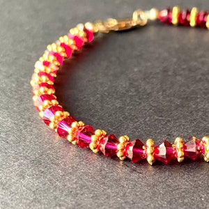 May include: A red and gold beaded bracelet with a clasp fastening. The bracelet is made with small, faceted beads.
