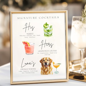 May include: A framed sign with gold trim displays a list of signature cocktails. The sign includes watercolor illustrations of a Mojito, a Grapefruit Gin Fizz, and an Orange Martini. A golden retriever is also pictured.